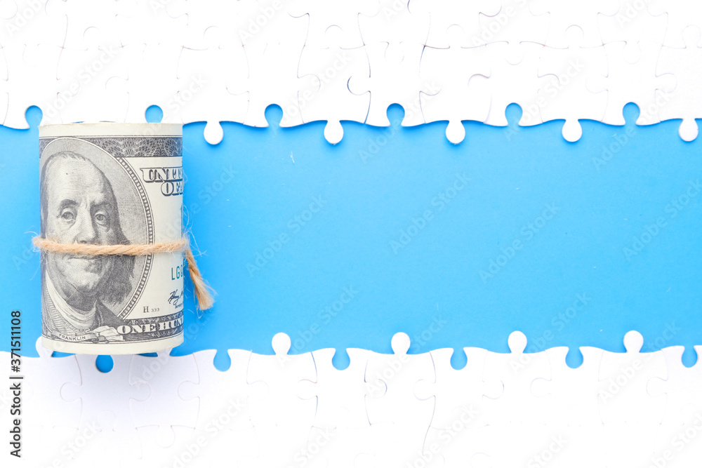 Wall mural a picture of money with separated jigsaw puzzle with copy space blue background. financial solution 