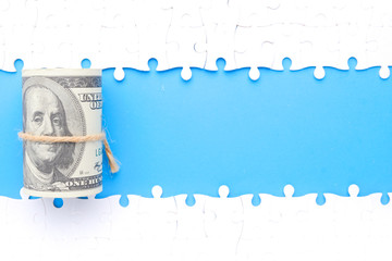 A picture of money with separated jigsaw puzzle with copy space blue background. Financial solution concept.