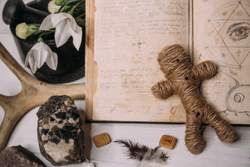 A voodoo doll made of rope lies with old book grimoire