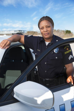Policewoman standing in door of Police car looking towards camera 