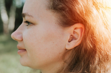 small intra channel hearing aid in the ear of a woman. flare