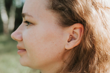 small intra channel hearing aid in the ear of a woman