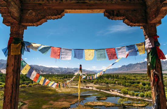 India, Ladakh, Colorful prayer flags hanging between two old columns