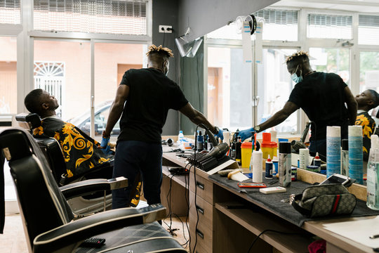 Young man relaxing on chair while barber working in hair salon