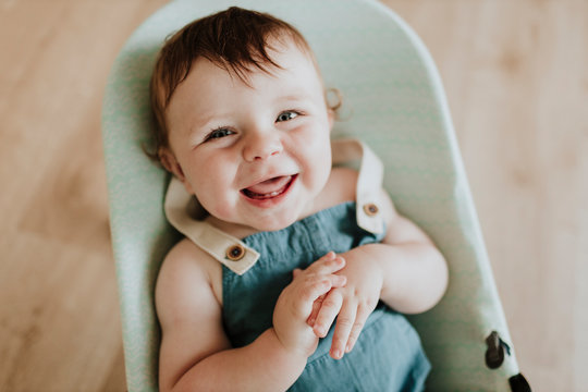 Close-up of cheerful cute baby girl lying in moses basket at home
