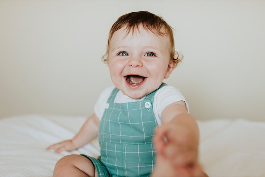 Close-up of baby girl laughing while sitting on bed at home