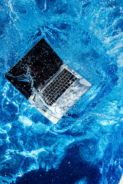 High angle view of computer falling in swimming pool