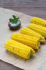 Young yellow fried sweet corn on craft paper. Delicious summer food. Close-up.