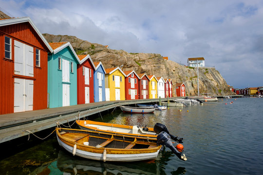 Sweden, Vastra Gotaland County, Smogen, Boats moored in front of colorful boathouses