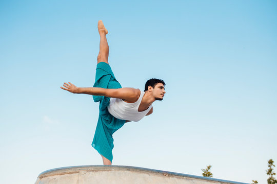 Young man doing rhythmic gymnastics exercise against clear blue sky