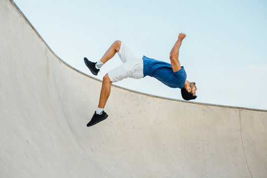 Young man doing wallflip on sports ramp against sky