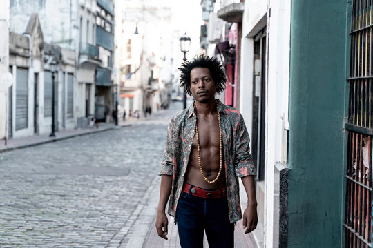 Thoughtful retro man wearing unbuttoned shirt while walking on sidewalk