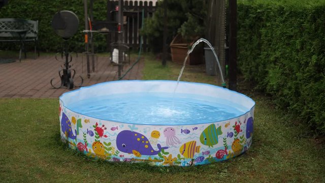 Filling up Childrens Kids swimming snapset Pool. Hose flexible pump water pipe. Summer BBQ outdoors. Isolated.