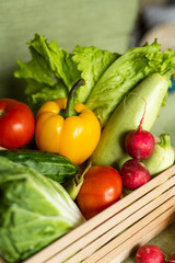 Fruits and veggies in wood box with green background.
