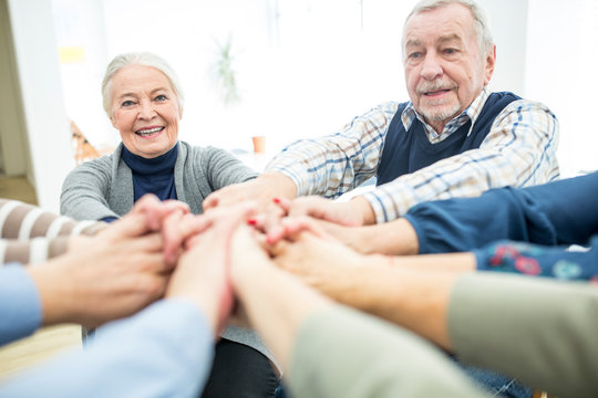 Group of active seniors stacking hands, symbolizing solidarity