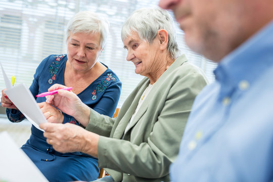Seniors in therapy group in retirement home writing down notes on sheets of paper