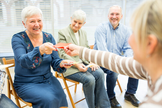 Seniors in retirement home attending group therapy using colorful paper cards - Powered by Adobe