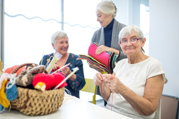 Senior women knitting toghether in needlework group of retirement home