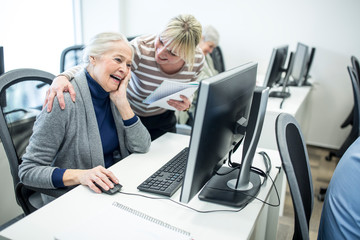 Active seniors attending computer course, intructor giving advice