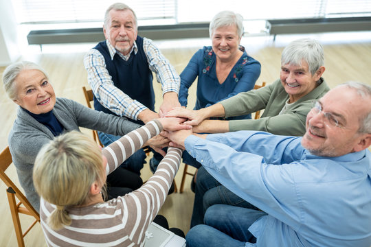 Group Of Active Seniors Stacking Hands, Symbolizing Solidarity