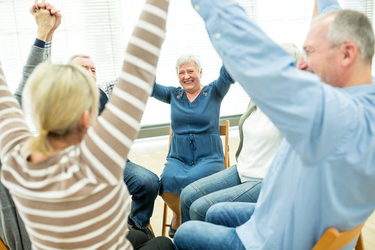 Group of seniors practicing chair gymnastics with instructor  in retirement home