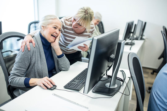 Active seniors attending computer course, intructor giving advice