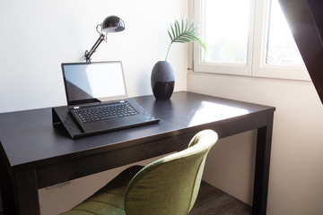 Workplace with laptop on table at home near window, modern interior home office desk on a sunny day stylish decoration