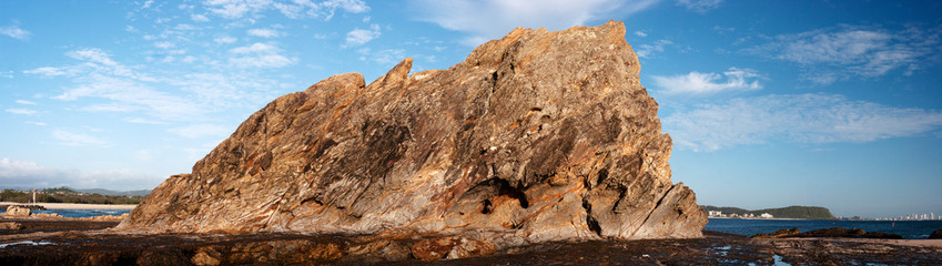 Panoramic shot of a big rock near the coastline