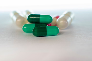 green capsules of manipulated medicine with blurred background