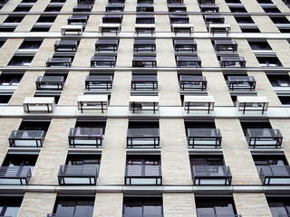 Modern city architecture photography. Image of a contemporary apartment building or multiple-dwelling house. It has many windows and small balconies.