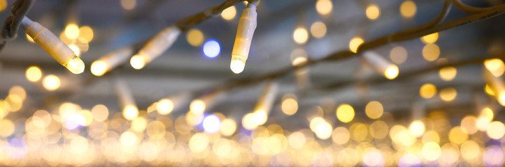 blurred glowing lights of garlands of golden color, bokeh. banner
