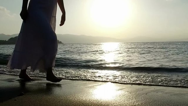 Footage of a girl running along the coast at sunset, in slow motion.