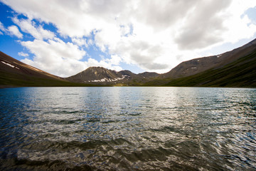 Alpine mountain lake at the daytime, sunlight and colorful landscape in Khazbegi, Georgia.