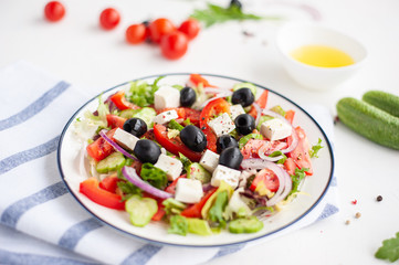 Greek vegetable salad with feta cheese and ingredients from which it is cooked on a white concrete background.