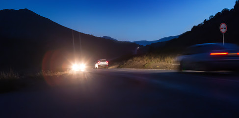 Cars move on a night road in the mountains.