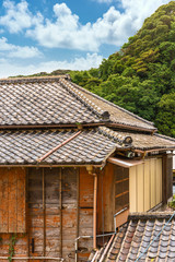 Fototapeta na wymiar Close-up on a hip roof named yosemunezukuri ornate with decorative Onigawara tile at the end of the ridge and wooden facade named sasarako-shitami of a old traditional Japanese ryokan guesthouse.