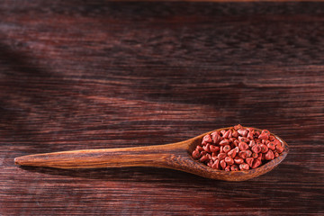 Annatto seeds in bowl on wooden background - Bixa Orellana.