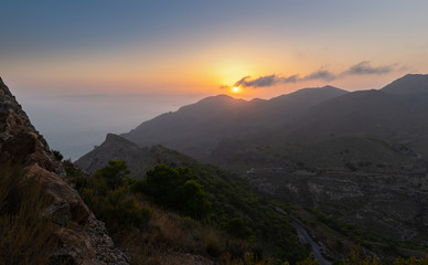 Obraz premium Sunset on the Costa Calida in Spain. The view from the mountain is directed to the south. The Mediterranean is in the haze. In the foreground are deep valleys.