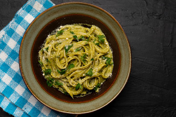 Creamy green pasta with poblano pepper and parmesan cheese on dark background