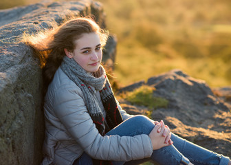 A girl sitting on top of hill against an amazing landscape in the autumn