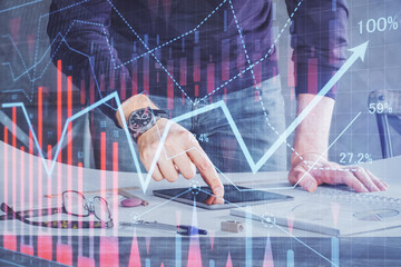 Double exposure of man's hands holding and using a digital device and forex graph drawing. Financial market concept.