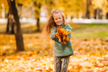 Portrait of adorable little girl with yellow leaves bouquet in fall