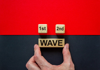 Symbol for a second wave of the corona virus. Hand holds cube with words '1st, 2nd, wave'. Copy...