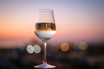 A glass of champagne on the blurred natural background of the sunset. Close-up of a glass of white wine with a copy of the space. Festive evening. Soft focus, beautiful bokeh.