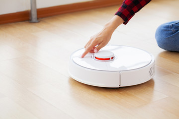 Close up of woman turns on smart robot vacuum cleaner