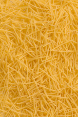 Raw vermicelli pasta background. raw yellow vermicelli is scattered on the table. raw yellow vermicelli scattered randomly on the table. short raw yellow vermicelli for cooking