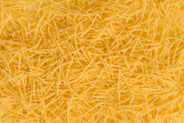 Raw vermicelli pasta background. raw yellow vermicelli is scattered on the table. raw yellow vermicelli scattered randomly on the table. short raw yellow vermicelli for cooking
