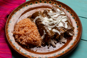 Mexican chicken enchiladas with mole sauce and rice on turquoise background