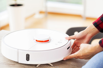 Close up of woman turns on smart robot vacuum cleaner