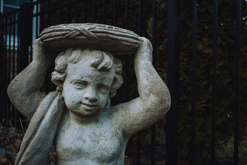 Obraz premium A Small Cherub Statue Holding a Plate Over Its Head